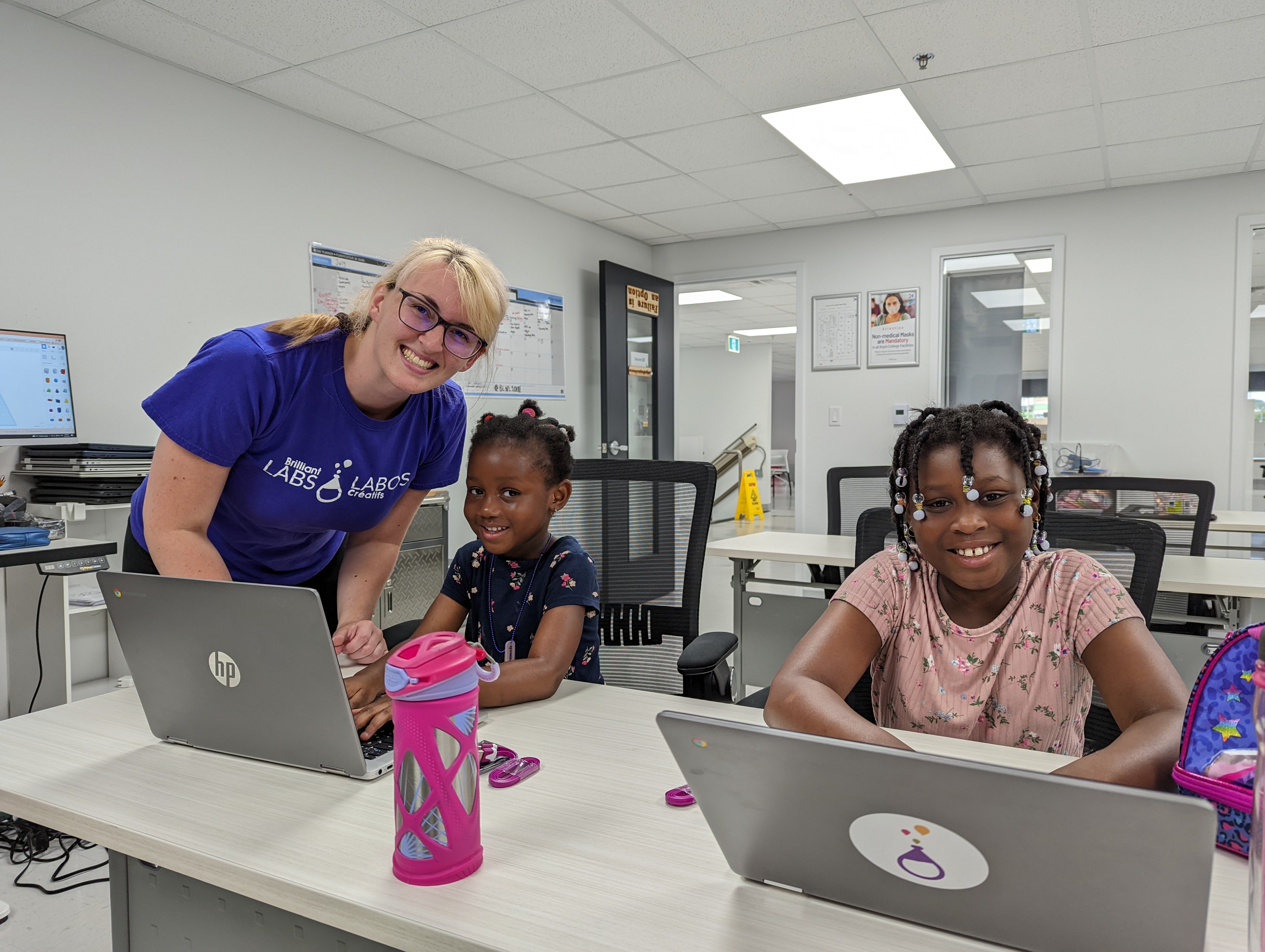 A Brilliant Labs STEAM mentor helping two students on laptops